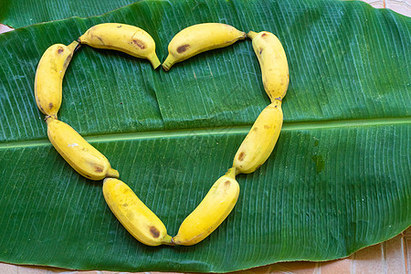 黄色香蕉的平面布局 以绿色香蕉叶上的心脏形式呈现出来情调茶点热带饮食异国团体水果食物素食主义者农业图片