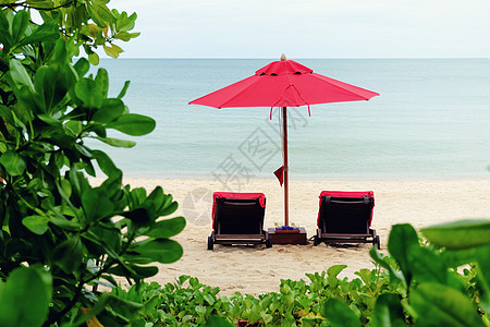 红伞在沙滩上旅游天堂闲暇日落热带太阳天空海洋躺椅晴天图片