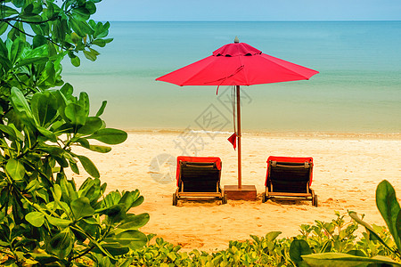 红伞在沙滩上支撑躺椅休息天堂酒店太阳海洋晴天海浪日落图片