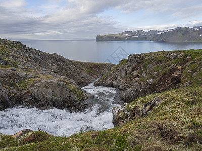 冰岛的霍恩斯特兰迪尔自然保护区 野生河流级联 绿草地和蓝天空白云背景 在冰上海湾自然保留区中图片