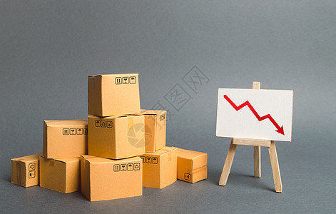 一堆纸板箱和画架 红色箭头向下 商品和产品的质量 价格 数量和竞争力下降 工业生产概念下降 销售下降图片