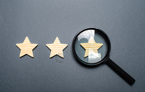 三颗星和灰色背景上的放大镜 三星级认证 评级欺诈 餐厅或酒店的评级和状态 声望 高质量和可靠性图片