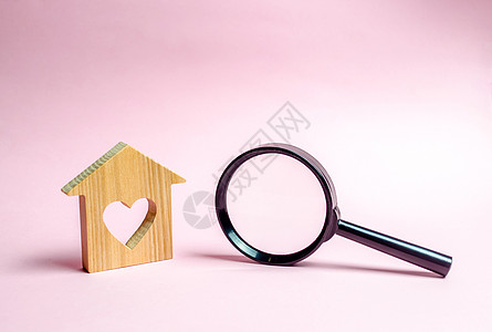 有心脏和放大镜的木房子 为年轻家庭和已婚夫妇提供经济适用房的概念 抵押 租个房子在情人节度过一个浪漫的假期图片