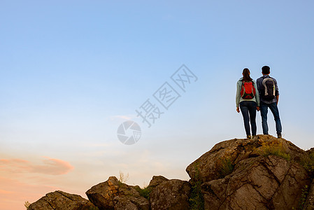 青年旅游者在夏季日落时站在岩石顶端 家庭旅行和冒险概念组织伴侣运动日出伙伴远足高度阳光朋友帮助救援图片
