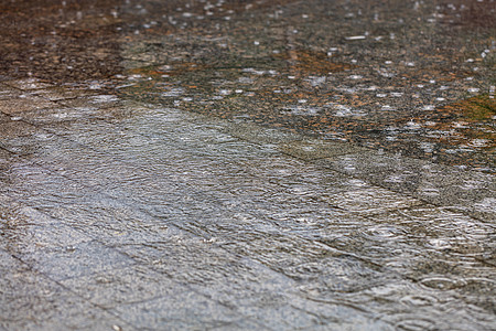 水面下雨时的同心圆环覆盖了城市人行道上的花岗岩地区图片