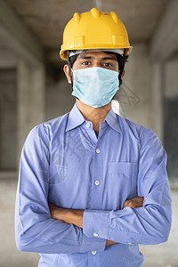 重返工作岗位 建筑工地开放的概念 — 由于冠状病毒或 covid-19 大流行 自信的男性建筑工人戴着带医用口罩的建筑头盔图片