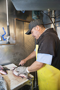 成熟的雄鱼渔捞手在桌上切鱼桌子食品职业男性菜刀成人工业批发市场市场海鲜图片