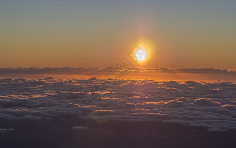 橙红色的日出 太阳升起在蓬松的云层之上 带着阳光和镜头光晕 从的顶部拍摄图片