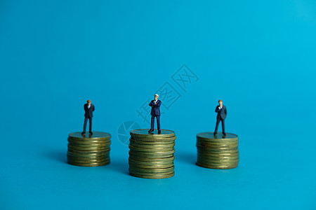 人站在钱上微型商业概念     商务人士站在金硬币堆架之上信用通货膨胀生长数字办公室工作男人银行业经济市场背景