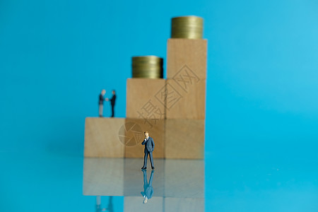 微型商业概念     思想商务人士站在木块前 手持硬币堆叠和2个握手男子图片