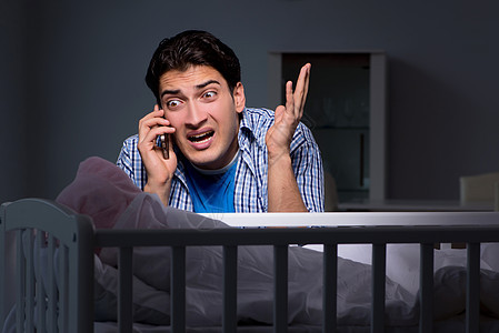 年轻父亲因夜间婴儿哭泣而承受压力家庭男人孩子童年婴儿床母性父母气体电话护理图片