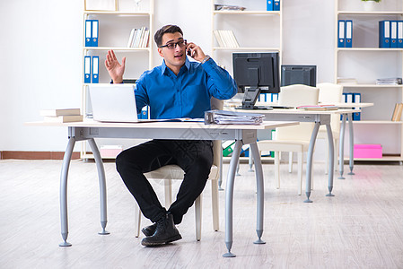 电脑和手机坐在办公室办公桌前的英俊商工雇员商务公司电话金融经理男人电脑企业家报告员工背景