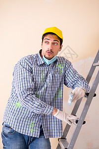年青的承包商用砂纸铺沙墙梯子工具维修装修绘画房子公寓修理工服务工作图片