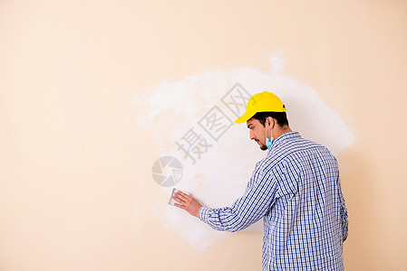 年青的承包商用砂纸铺沙墙建筑绘画维修服务装修职业滚筒装潢师房间房子图片