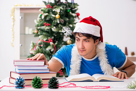 圣诞节前夕带书的年轻学生教育庆典读者图书男人桌子大学研究考试阅读图片