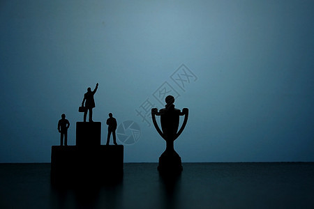 商业战略概念照片微型商务人士站在领奖台上指着奖杯的剪影男人导航塑像竞赛冠军办公室讲台金子公司数字图片