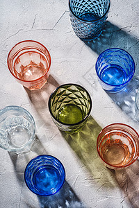 彩色面板和几何式饮料杯 一组空饮料器酒吧酒具阳光石头不倒翁反射玻璃光束蓝色折射图片