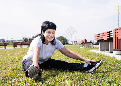 在公园的草地上坐着 满身笑容的老妇人身体运动员微笑娱乐运动装女性力量锻炼闲暇活动背景图片