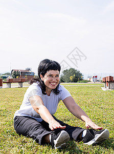 在公园的草地上坐着 满身笑容的老妇人闲暇运动运动员身体福利成人活动锻炼退休娱乐背景图片