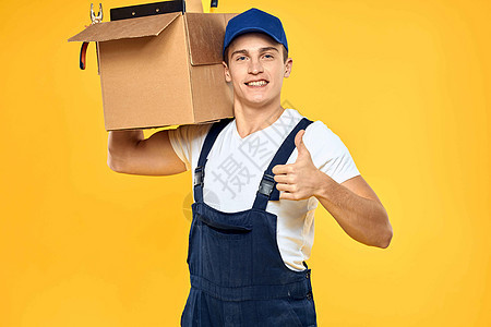 身穿制服 带箱式手送货装货服务的工人 黄色背景商务包装男人邮政工作重量运输商业领带成人背景图片