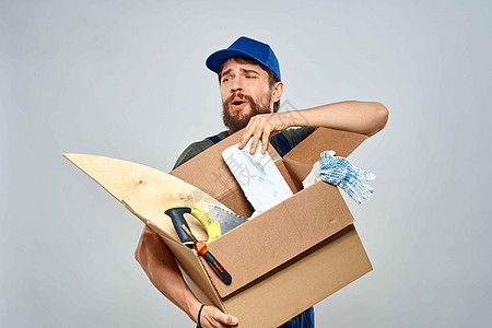 男子穿着工作制服和手持工具盒装箱的男人的生活方式邮件纸板成人重量服务蓝色运输船运商务包装背景图片