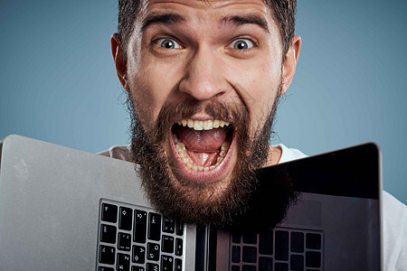 以蓝背景作物景色打开笔记本电脑的情感男子肖像互联网商务男性成人人士成功衬衫眼镜经理微笑图片