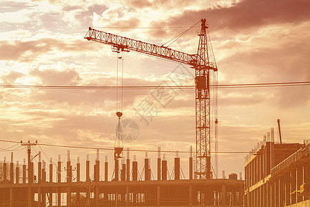 在日落天空背景下建一座建筑 由建筑工人组成的团队的轮廓和一台起重机组成工人工程施工就业承包商太阳日落劳动劳动力技术背景