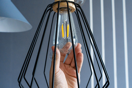 特写 手会改变一个灯泡 在时尚的阁楼灯 螺旋丝灯 现代室内装饰经济技术玻璃活力天花板插座服务生态螺旋白炽灯图片