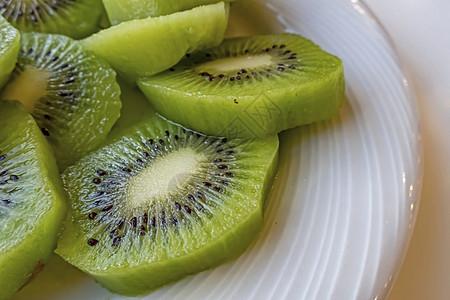 猕猴桃果园白盘上切碎的椰枣白色水果营养甜点绿色宏观小吃异国食物圆形背景