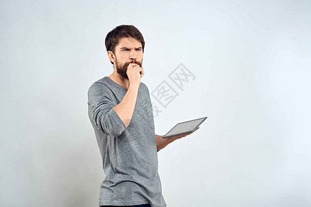 一个手手里拿着平板电脑的男人 互联网科技通讯灰色夹克光背景的白衣相机软垫商务人士屏幕男性工作室微笑药片快乐图片