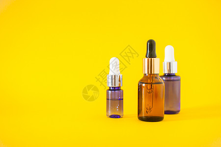 黄色背景上装有血清的化妆瓶 美容学和美貌概念卫生治疗液体胶原护理女士皮肤小样身体吸管图片