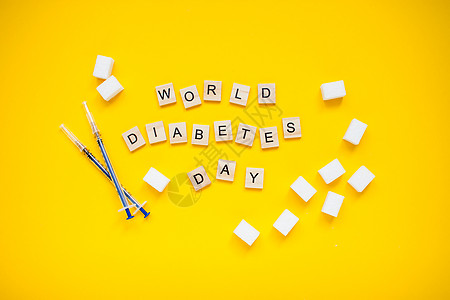 木块世界糖尿病日的铭文和黄色背景上压糖和胰岛素注射器的立方体图片