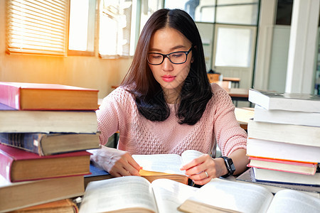 在图书馆学习的年轻女性青少年女孩教育微笑知识女士学生校园书架笔记本图片