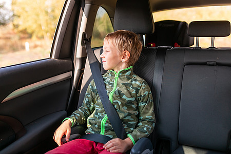 汽车座椅坐在助推座上的小男孩在车里系好安全带安全驾驶腰带助推器家庭椅子座位婴儿孩子预防背景