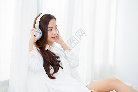 美丽的亚洲年轻女子喜欢听有耳机的音乐吗睡衣女士乐趣闲暇女性房间互联网卧室公寓快乐图片