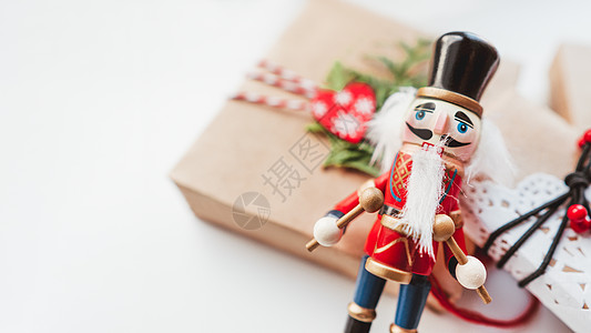 用牛皮纸和木制胡桃夹子玩具包裹的圣诞 DIY 礼物 新年礼物上的装饰 节日背景 寒假精神 与复制空间的白色背景图片