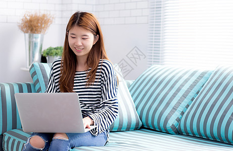 使用笔记本电脑休闲的年轻亚洲妇女肖像美丽成人女孩互联网客厅微笑沙发假期闲暇女士商业生活方式高清图片素材