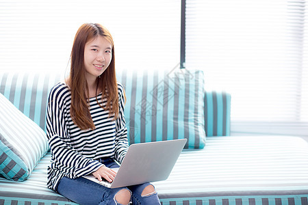使用笔记本电脑休闲的年轻亚洲妇女肖像美丽女孩女士技术自由职业者沙发互联网房子成人客厅微笑生活方式高清图片素材