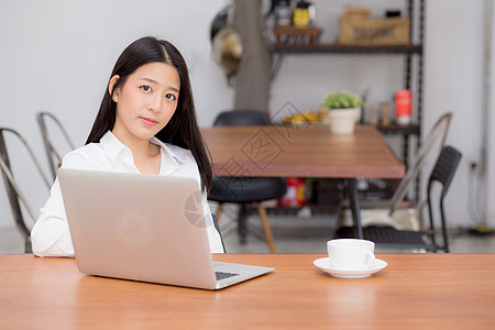 在网上用笔记本电脑工作的美丽的亚洲年轻女性女士桌子上网博客互联网女孩成人商务潮人咖啡咖啡店图片
