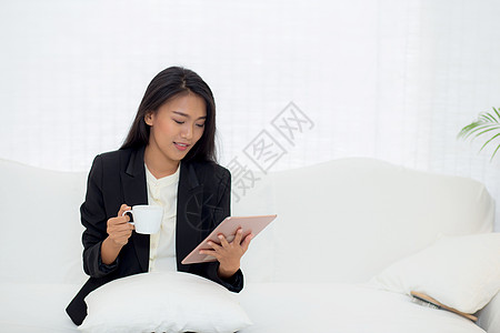 坐在沙发上的年轻亚洲女商务人士的美丽肖像客厅互联网商务技术咖啡女孩手机女性管理人员女士图片