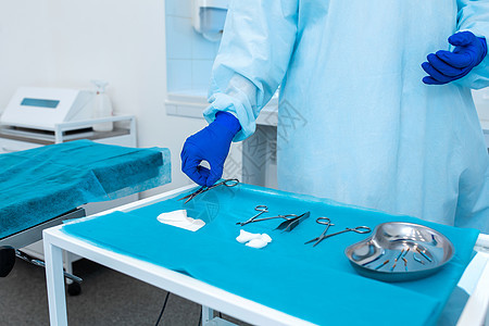 穿着睡袍和手套的护士在外科手术前拿出消毒器械图片