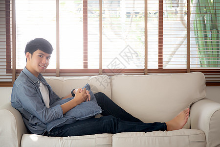 长着肖像的年轻英俊的亚洲男人 在沙发上舒适地睡着放松房子公寓幸福微笑长椅房间人士成人商业福利图片