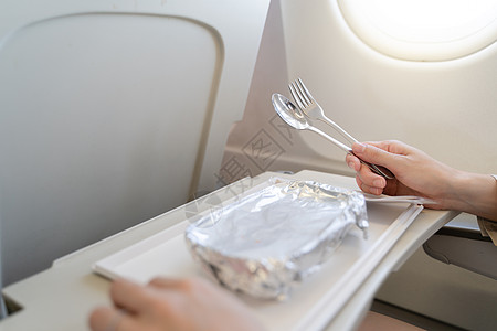 飞手飞机上装着食品盘子 在Ec上服餐的妇女班级假期航空公司飞行早餐服务午餐食物喷射托盘背景