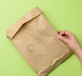 两只手拿着纸袋 包着棕色的Kraft纸解雇店铺零售空白商品折叠生态午餐食物营销图片