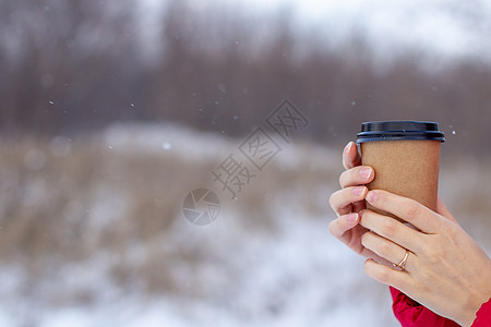 冬天的年轻女子 喝杯热咖啡或茶雪花公园纸板工作商业手套液体饮料女孩杯子图片