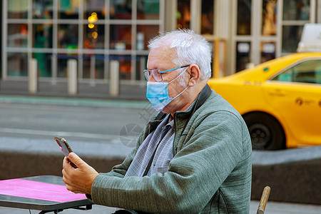 在纽约大流行病旅行期间 老人戴着手机走在街上 以保护自己免受冠状病毒感染图片