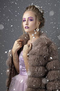 漂亮的模特 在毛皮大衣上化妆时很时髦 身穿灰色背景雪花的奢华冬夜女孩图片