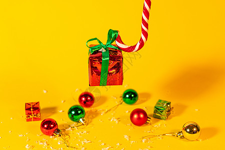糖果手杖棒棒糖拿着一个礼盒 里面有黄色背景的圣诞礼物 圣诞糖果和新年装饰风格薄荷假期盒子甘蔗甜点礼物装饰品送货季节图片