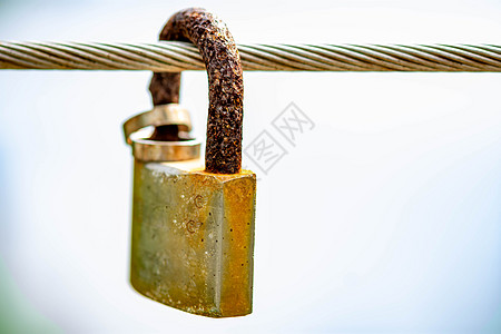 Rusty 挂在金属缆绳上 戴着结婚戒指 象征着婚姻和永远的爱夫妻友谊场景栅栏挂锁图片
