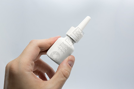 年轻人生病用鼻腔喷雾剂治疗鼻塞 喷鼻药水 手持鼻腔喷雾剂 特写药丸包在病人手中图片